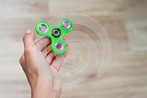 Fidget spinner. Green hand spinner, fidgeting hand toy rotating on child`s hand. Stress relief. Anti stress and