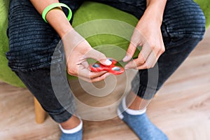 Fidget spinner. Red hand spinner, fidgeting hand toy rotating on child`s hand. Stress relief. Anti stress and relaxation adhd att