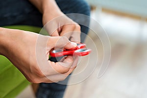 Fidget spinner. Red hand spinner, fidgeting hand toy rotating on child`s hand. Stress relief. Anti stress and relaxation adhd att