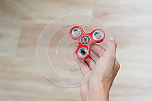 Fidget spinner. Red hand spinner, fidgeting hand toy rotating on child`s hand. Stress relief. Anti stress and relaxation adhd att