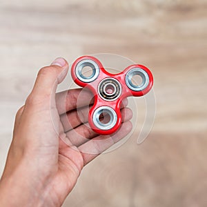 Fidget spinner. Red hand spinner, fidgeting hand toy rotating on child`s hand. Stress relief. Anti stress and relaxation adhd att