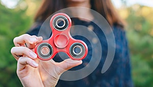 Fidget Spinner. Red sfidget pinner in a girl hand. photo