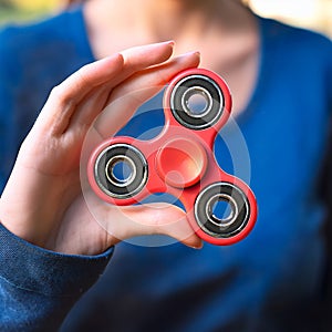 Fidget Spinner. Red sfidget pinner in a girl hand. photo