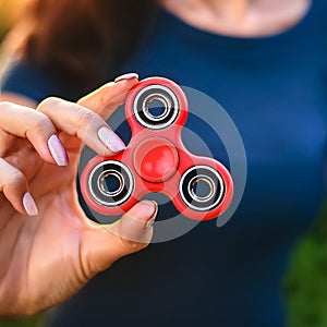 Fidget Spinner. Red sfidget pinner in a girl hand. photo