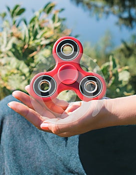 Fidget Spinner. Red sfidget pinner in a girl hand. photo