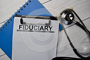 Fiduciary text write on a paperwork and stethoscope isolated on office desk