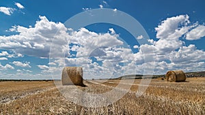 Field with bales of hay and beautiful sky time lapse