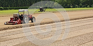 Field cultivated with lettuce and tractor during sowing of littl