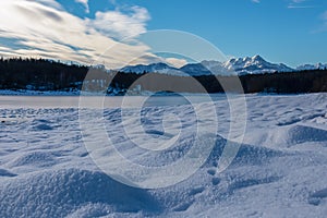 Field of deep crystal snow with scenic view of frozen alpine lake Forstsee, Techelsberg, Carinthia (Kaernten), Austria, Europe