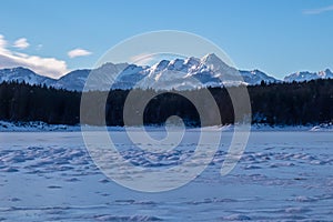 Field of deep crystal snow with scenic view of frozen alpine lake Forstsee, Techelsberg, Carinthia (Kaernten), Austria, Europe