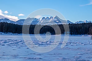 Field of deep crystal snow with scenic view of frozen alpine lake Forstsee, Techelsberg, Carinthia (Kaernten), Austria, Europe