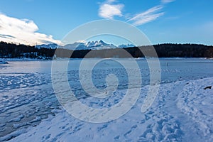 Field of deep crystal snow with scenic view of frozen alpine lake Forstsee, Techelsberg, Carinthia (Kaernten), Austria, Europe