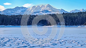 Field of deep crystal snow with scenic view of frozen alpine lake Forstsee, Techelsberg, Carinthia (Kaernten), Austria, Europe