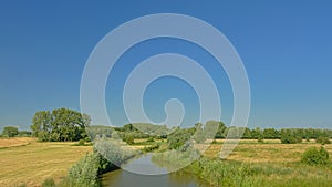 Field with ditch with reed and trees in Kalkense Meersen nature reerve, Flanders, Belgium