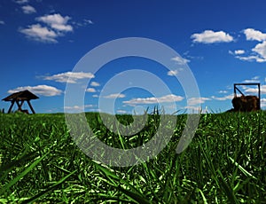 Field of green grass with wooden seesaw and stack of hay