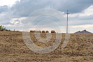 Field on the hill - stubble - baled straw on the ridge of the hill .