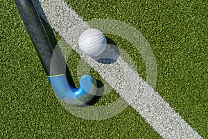 Field hockey stick and ball on the green field