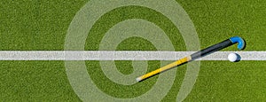 Field hockey stick and ball on green grass