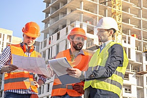 Field Inspectors and manager at Building Construction Site checking blueprints