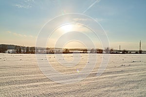 Field, meadow and grass with snow and cold sun on foggy cloudy sky. Beautiful winter landscape. Winter morning, day or