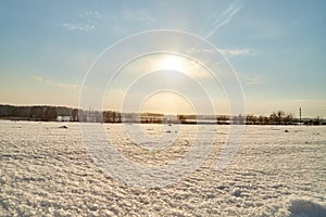 Field, meadow and grass with snow and cold sun on foggy cloudy sky. Beautiful winter landscape. Winter morning, day or