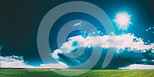 Field Or Meadow Landscape With Green Grass Under Scenic Spring Blue Dramatic Sky With White Fluffy Clouds. Rain Clouds