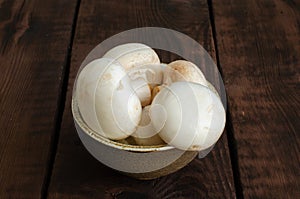 Field mushrooms in bowl on wooden background