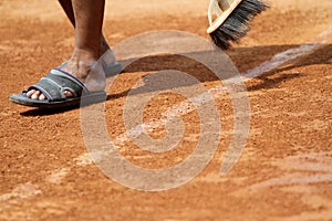 Field officers clean the clay tennis court lines with brooms before use