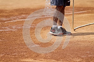 Field officers water the clay tennis court before use