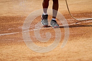 Field officers water the clay tennis court before use