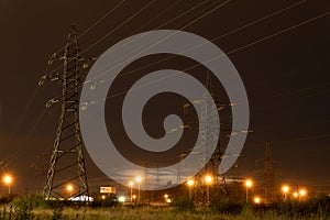 Field with power lines and illuminated streetlights at night - industry