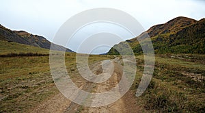 A field road ascending into a hollow between the mountains