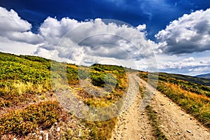 Field road in the mountains under the blue sky. Dramatic scene.