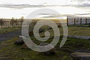 A field of rocks and grass with a fence in the background