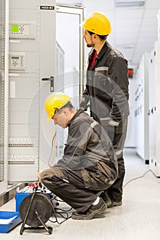 Field service engineers inspect system with relay test set equip