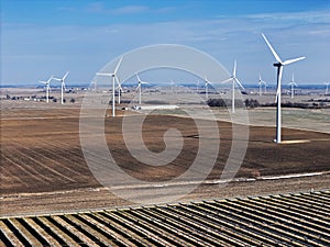 Field of solar panels with wind turbines in the background generating electric power