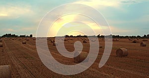 Field with Straw Bales Under Sunset Sky. 4k Aerial