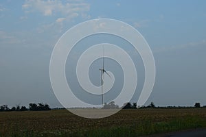 A field of windmills spin in front of a colorful evening sky. A wind turbine is used to produce electricity. Wind energy is the