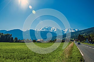Fields with houses and road, forest, alpine landscape and blue sky in Saint-Gervais-Les-Bains photo