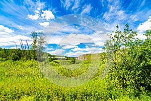 fields, meadows, ravines covered with green vegetation. Beautiful blue sky with white fluffy clouds. Summer landscape