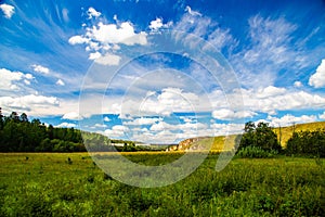 fields, meadows, ravines covered with green vegetation. Beautiful blue sky with white fluffy clouds. Summer landscape