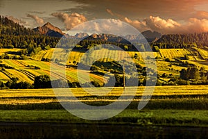 Fields and meadows on the slopes of the mountains. Polish rocky mountains in the background. Beautiful sunset in the countryside