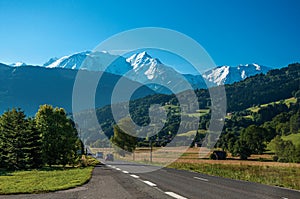 Fields, road, forest, alpine landscape and blue sky in Saint-Gervais-Les-Bains