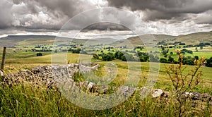 Fields and sheep on farm land in a valley with rain clouds