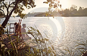 Fiends spend leisure time together at vacation on dock at sunset