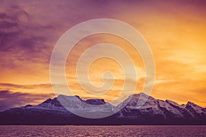 A fiery dawn over the snowy peaks of the fjord