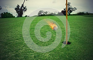 Fiery golf ball near the hole in a grass field