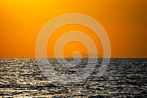 Fiery horizon, dramatic ocean sunset in vibrant hues over dark waters,