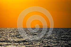 Fiery horizon, dramatic ocean sunset in vibrant hues over dark waters, photo