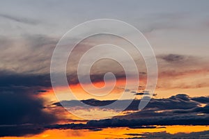 Fiery orange colorful sunset sky with fluffy clouds